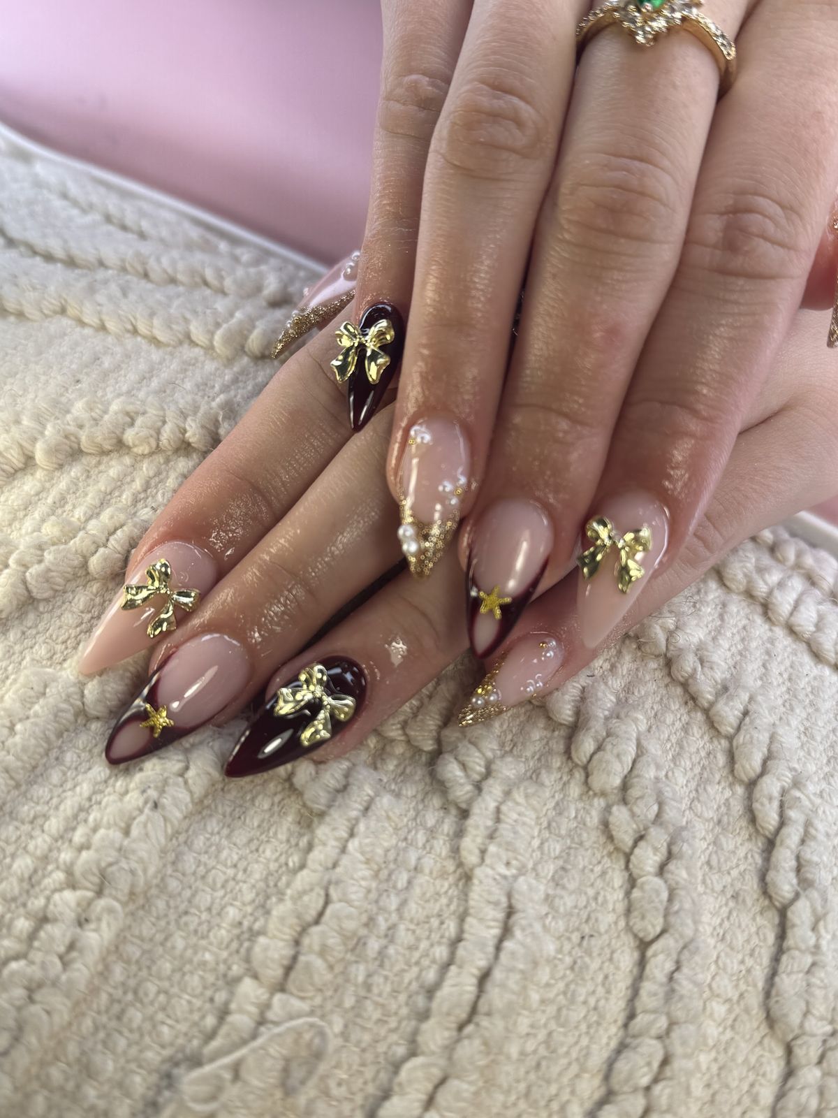 Nude amandelnagels met donkerbruine en gouden strikjes